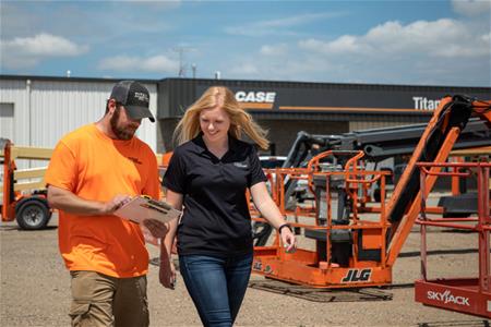 See female student learning from Titan employee at construction dealership