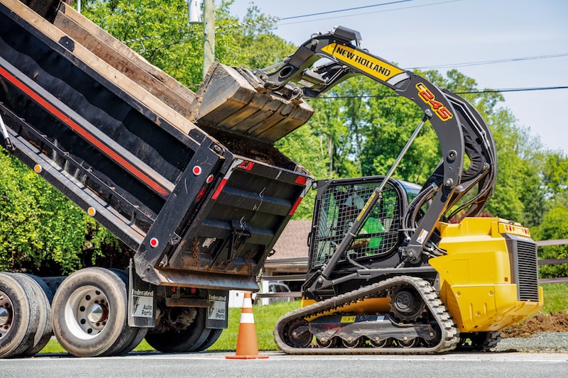 New Holland Construction C245 skid steer dumping into truck