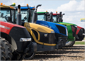 Pre_owned_ag_colorful tractor lineup Case IH, CAT, New Holland, and John Deere tractors lined up