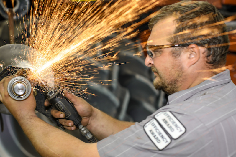 Service Page_Employee Service Technician working on Case IH equipment with a grinder